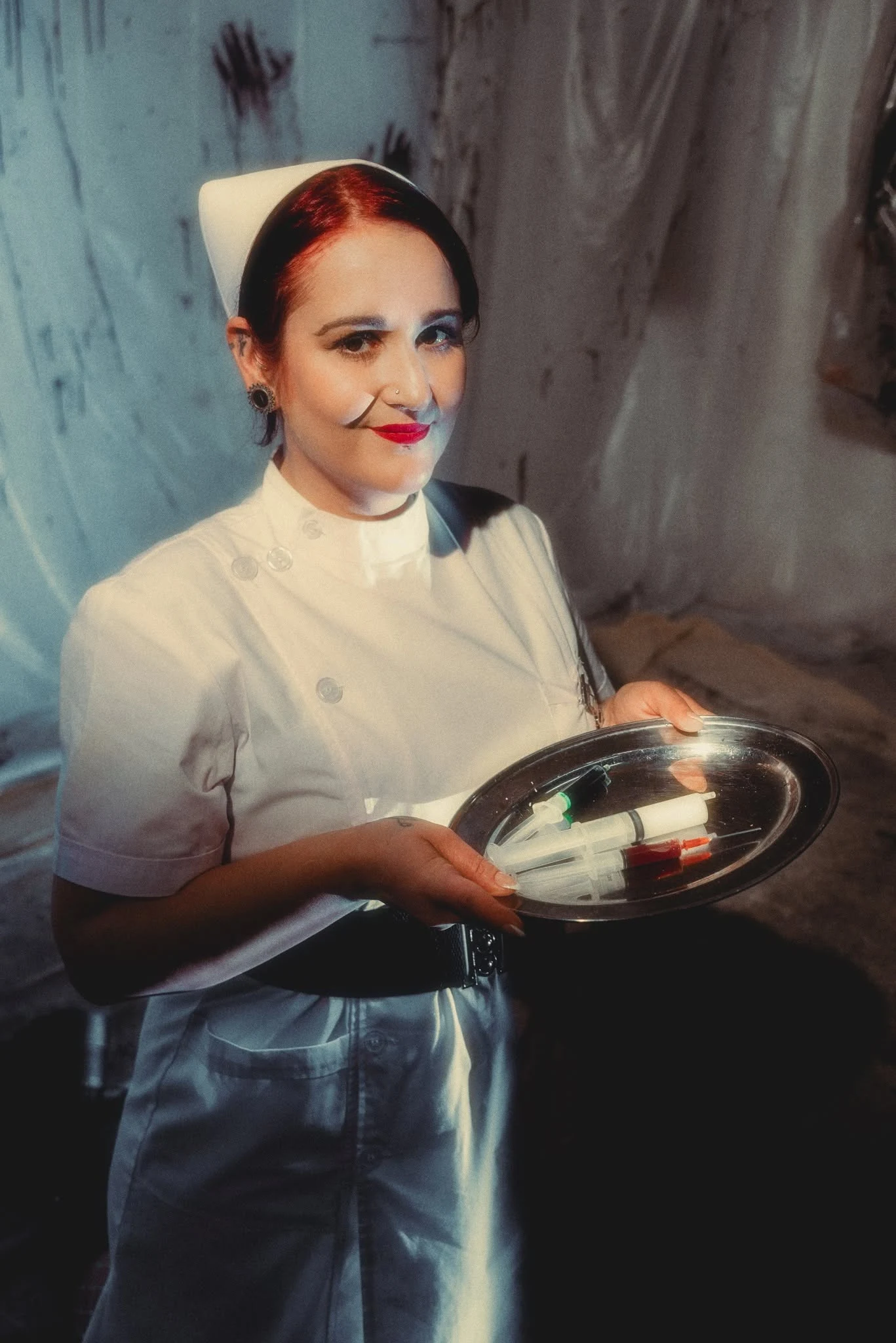 Nurse Betty holding a tray of theatrical medical props